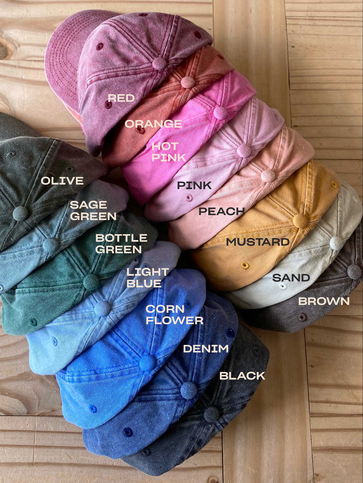 Stack of colorful baseball caps on a wooden surface with color labels.