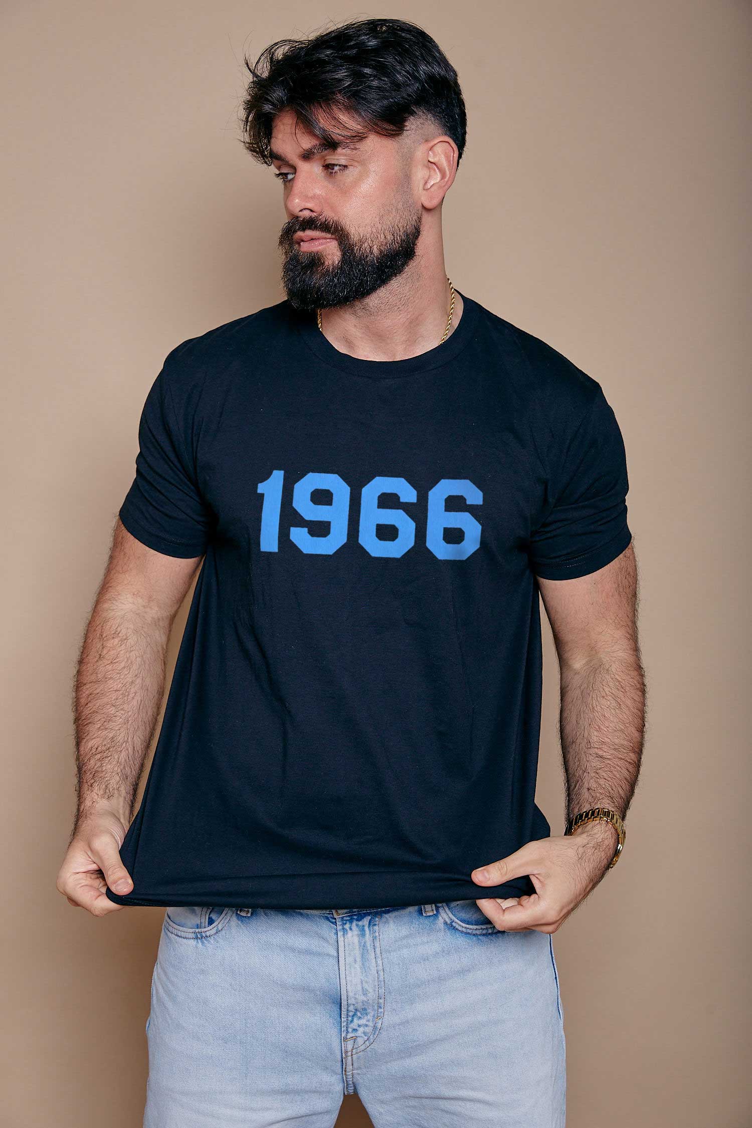 Man wearing a dark navy t-shirt with '1966' printed in blue on a beige background