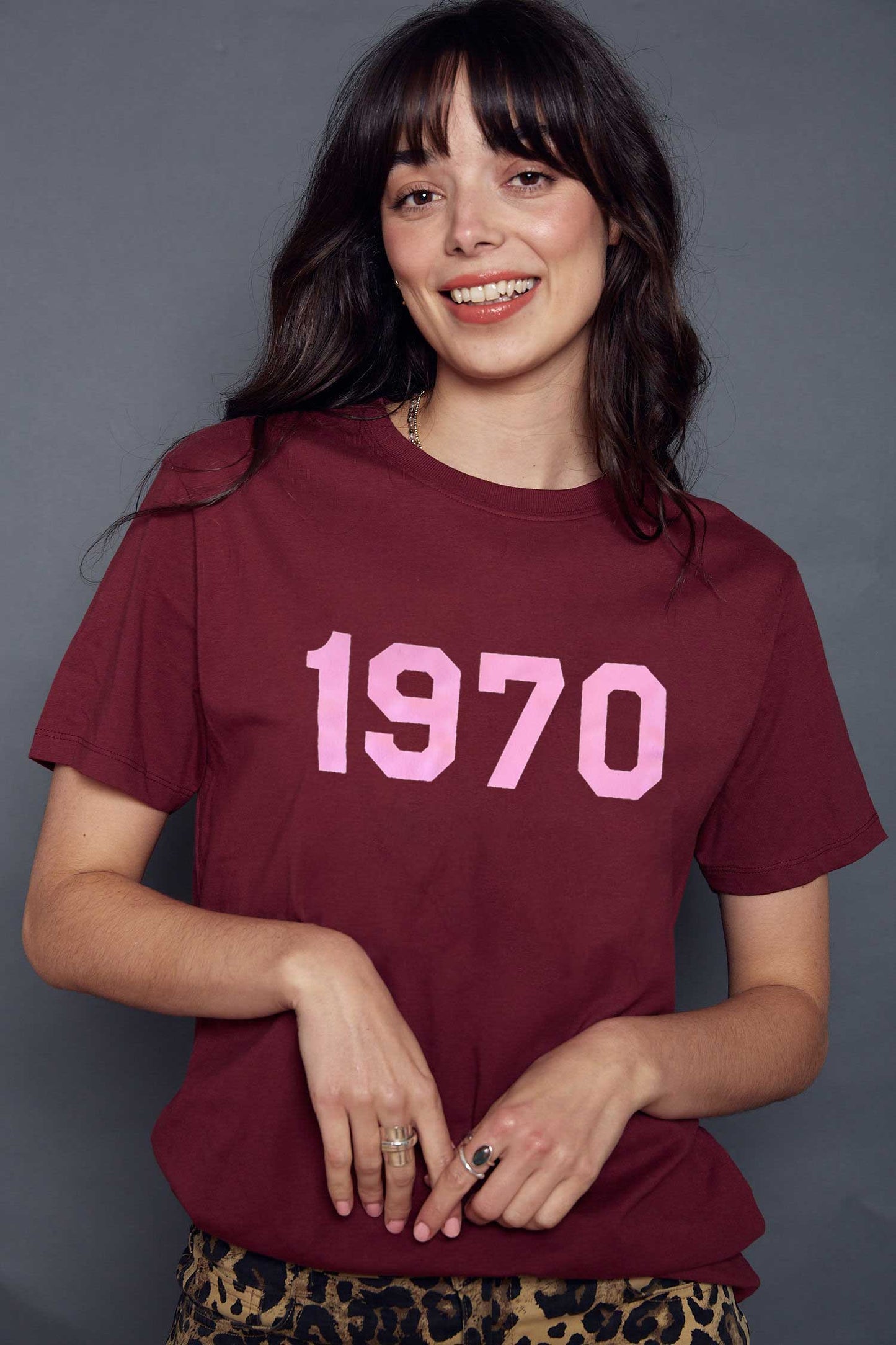 Woman wearing a maroon t-shirt with '1970' printed in pink on a grey background