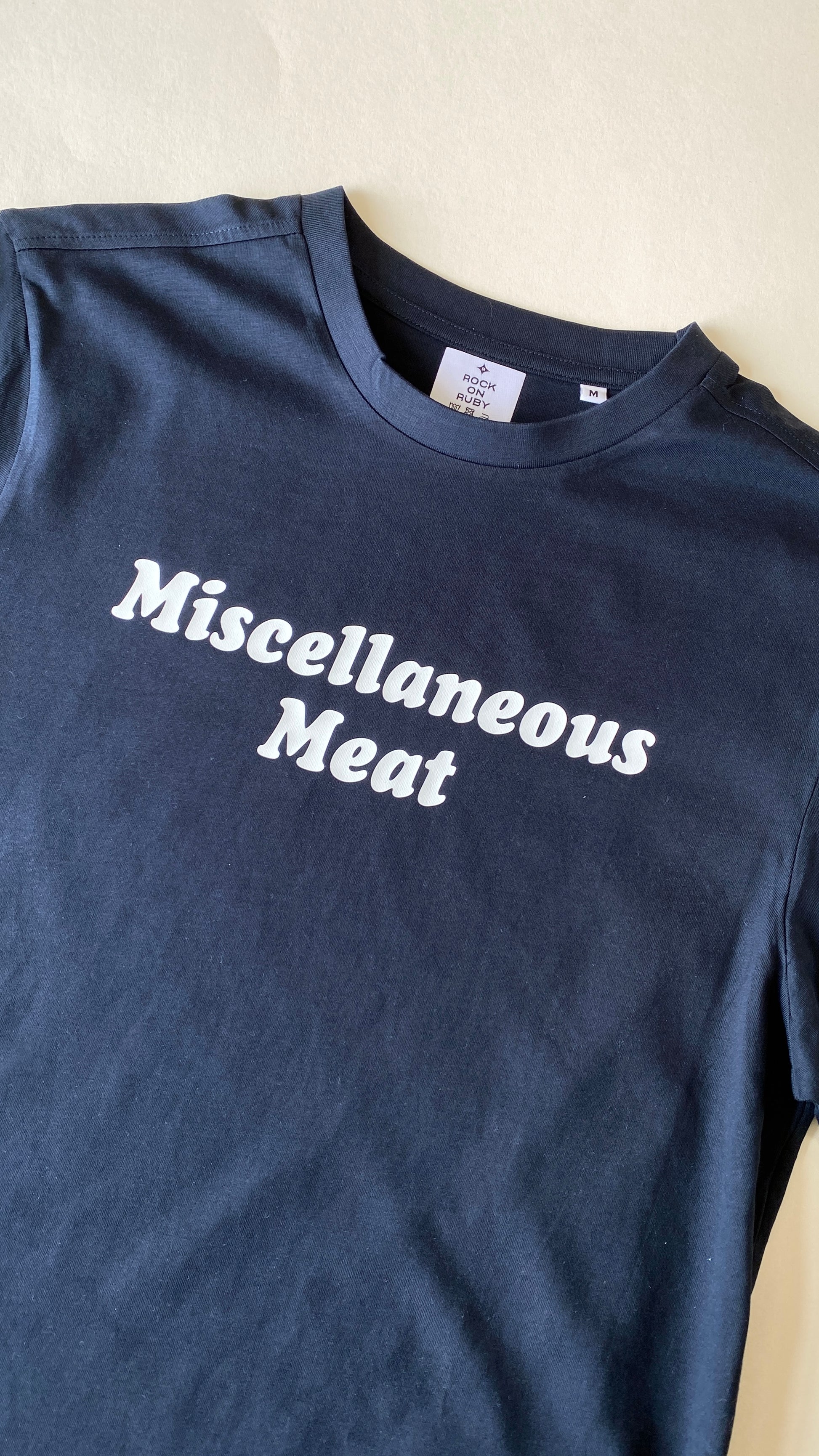 Navy blue t-shirt with 'Miscellaneous Meat' text on a beige background