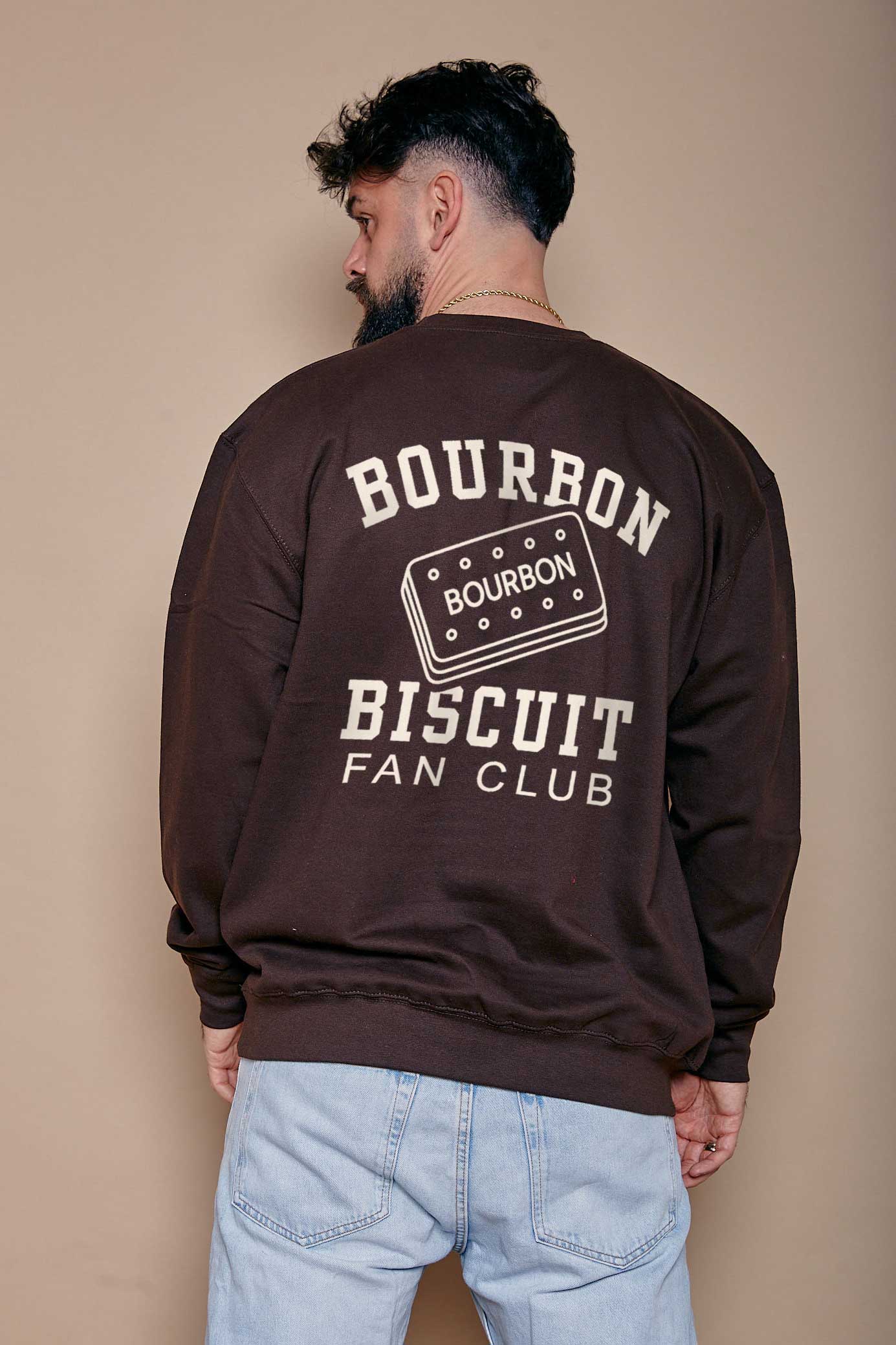 Man wearing a brown sweatshirt with 'Bourbon Biscuit Fan Club' text design on the back stood against a beige background