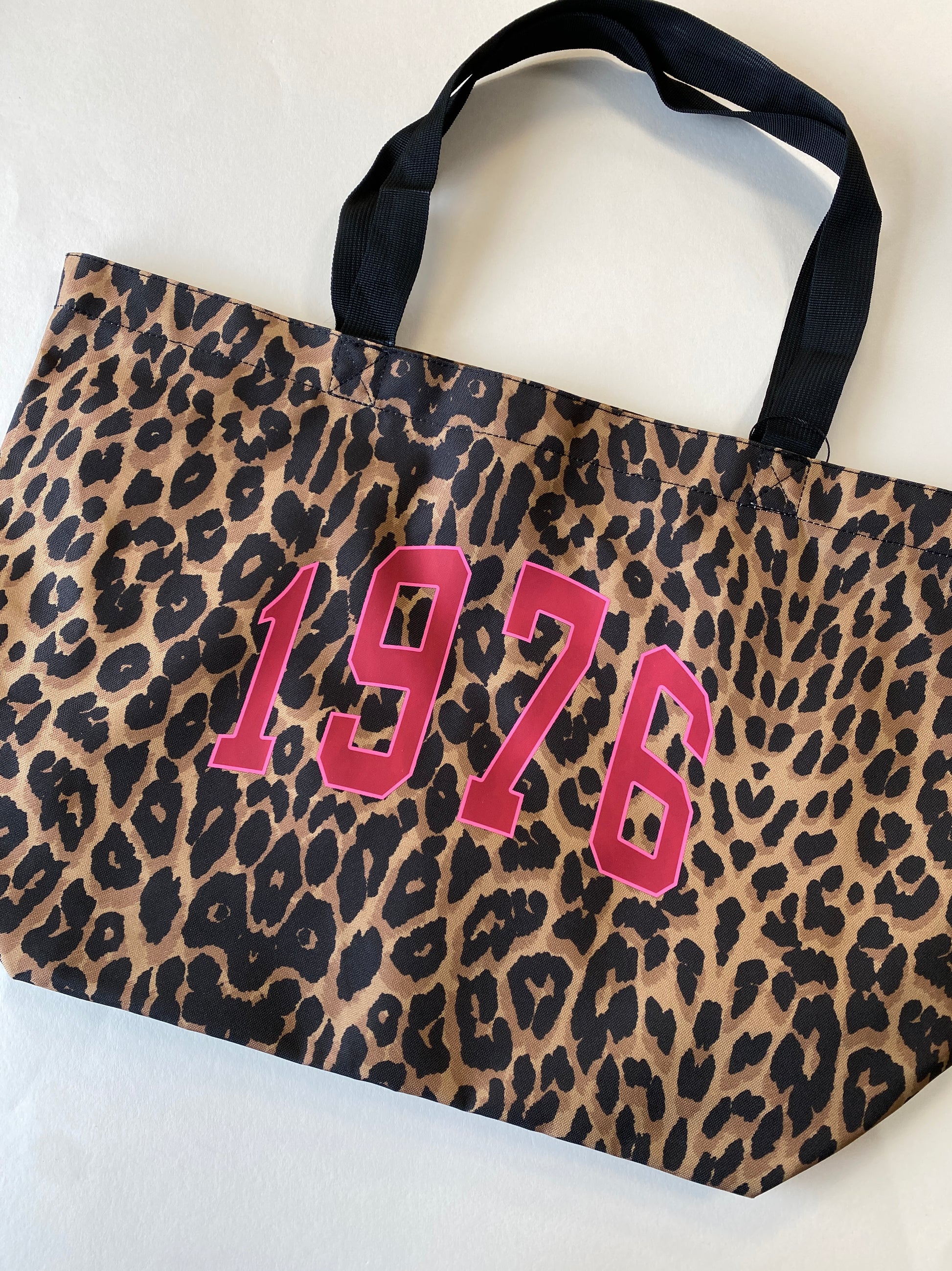 Leopard print bag with '1976' in pink on a white background