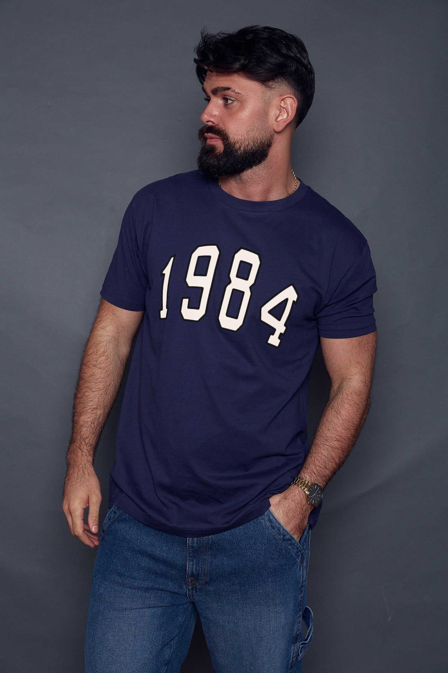 Man wearing a navy blue t-shirt with '1984' printed on it against a grey background