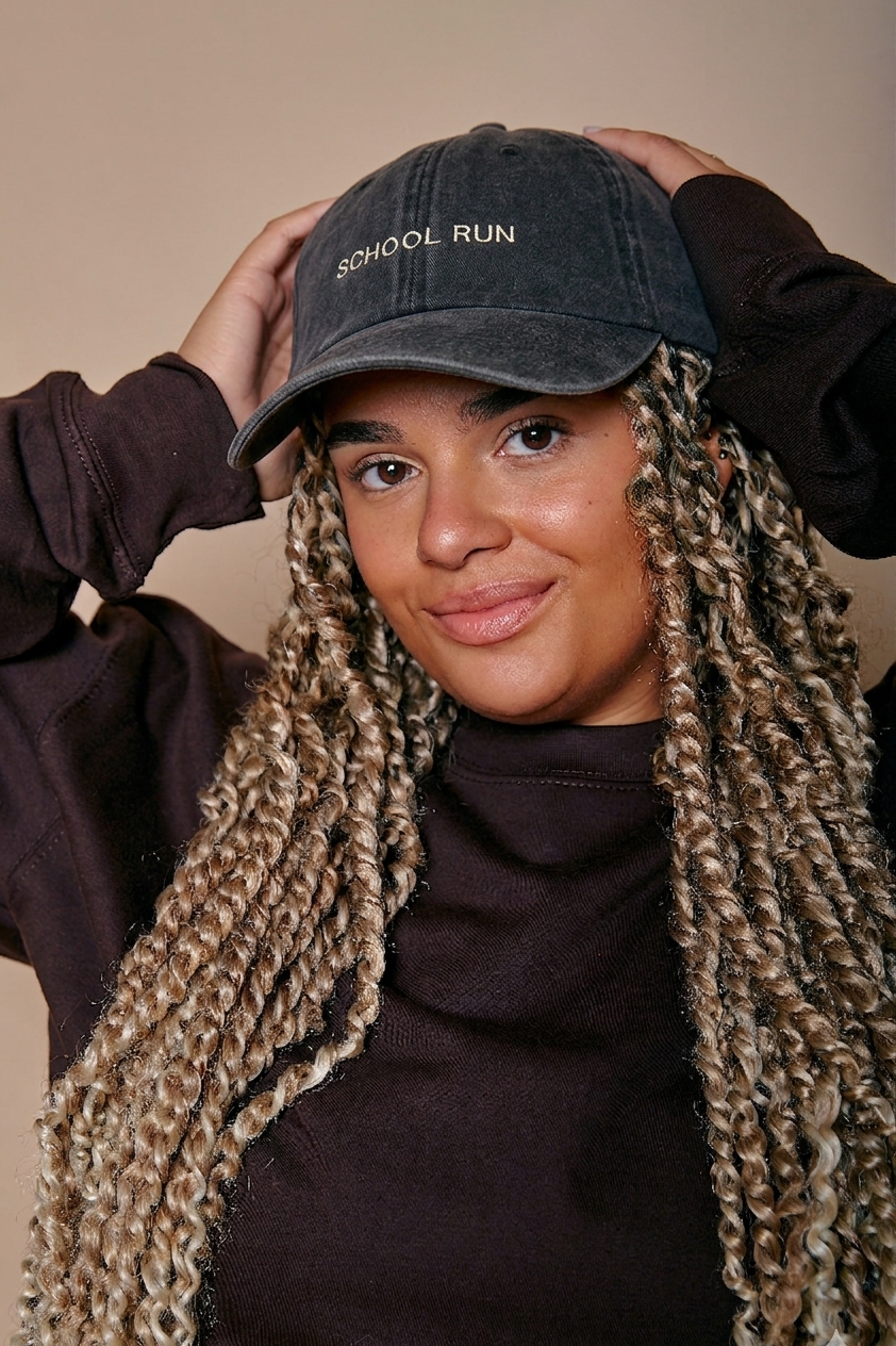 Person wearing a faded black cap with 'SCHOOL RUN' text, standing against a beige background.