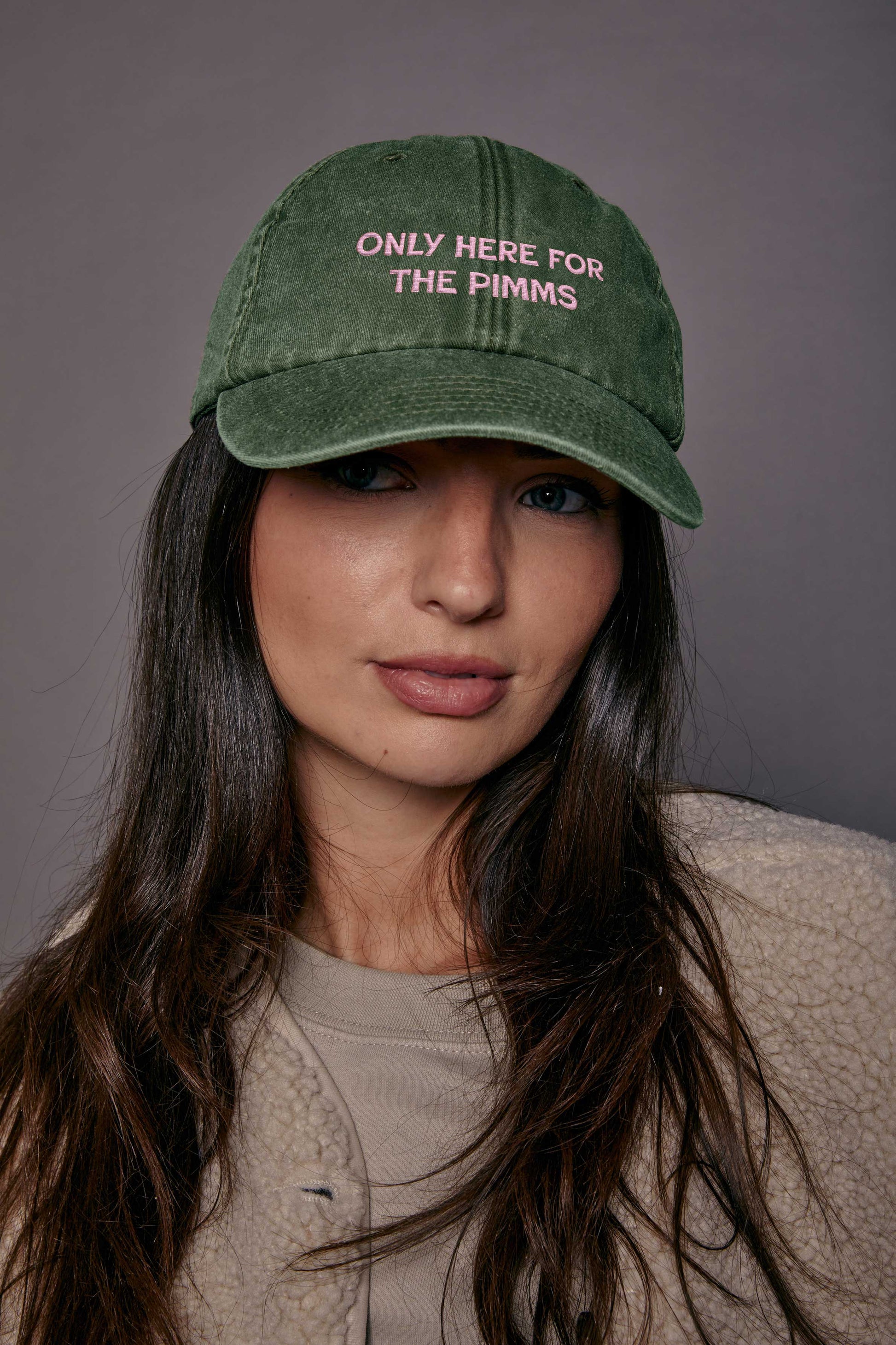 Person wearing a green cap with text, against a grey background