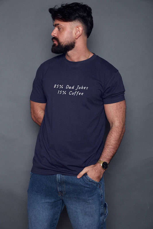 Man wearing a navy blue t-shirt with white text '85% dad jokes 15% coffee', standing against a grey background