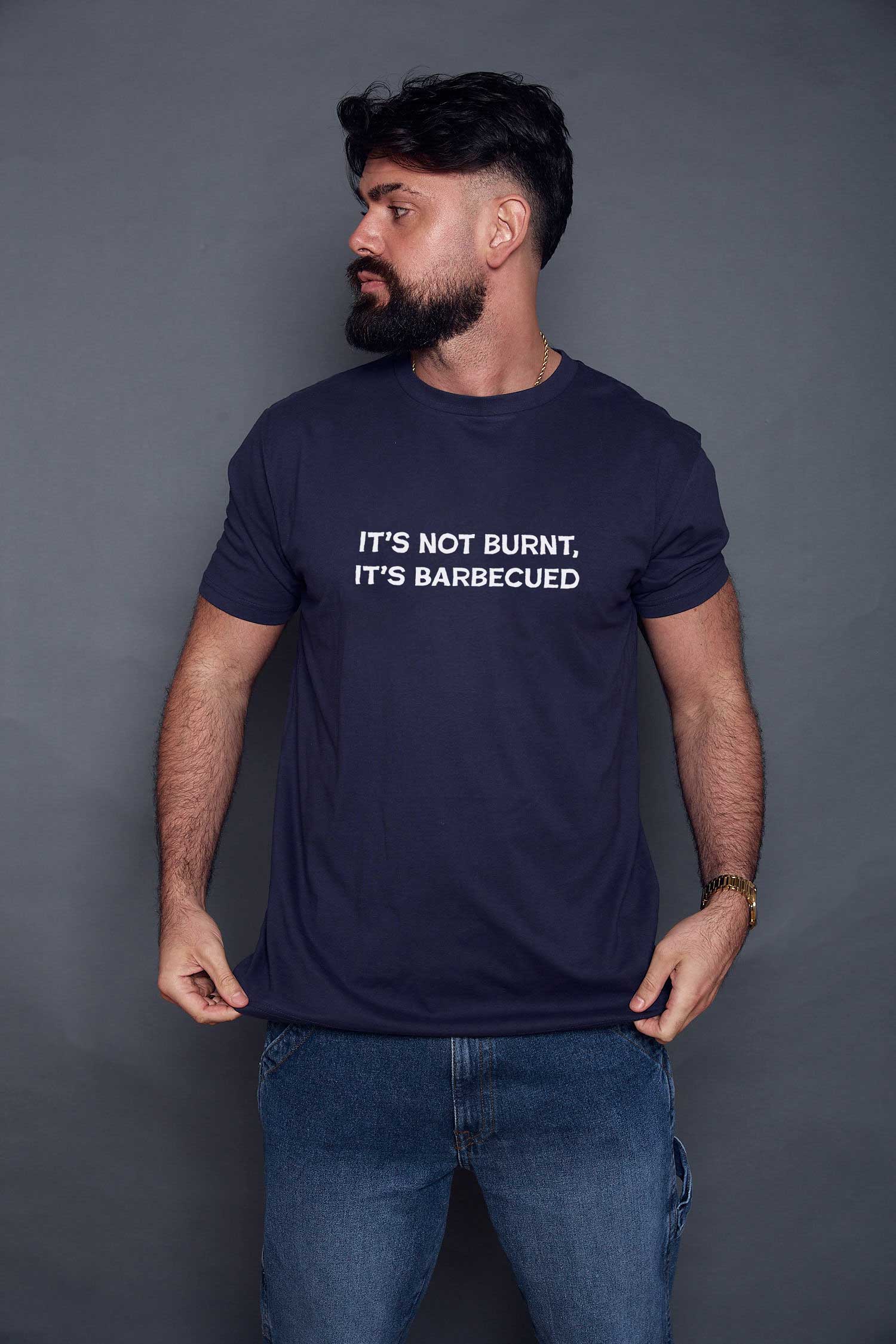 Man wearing a navy blue t-shirt with slogan 'it's not burnt, it's barbecued' on a grey background