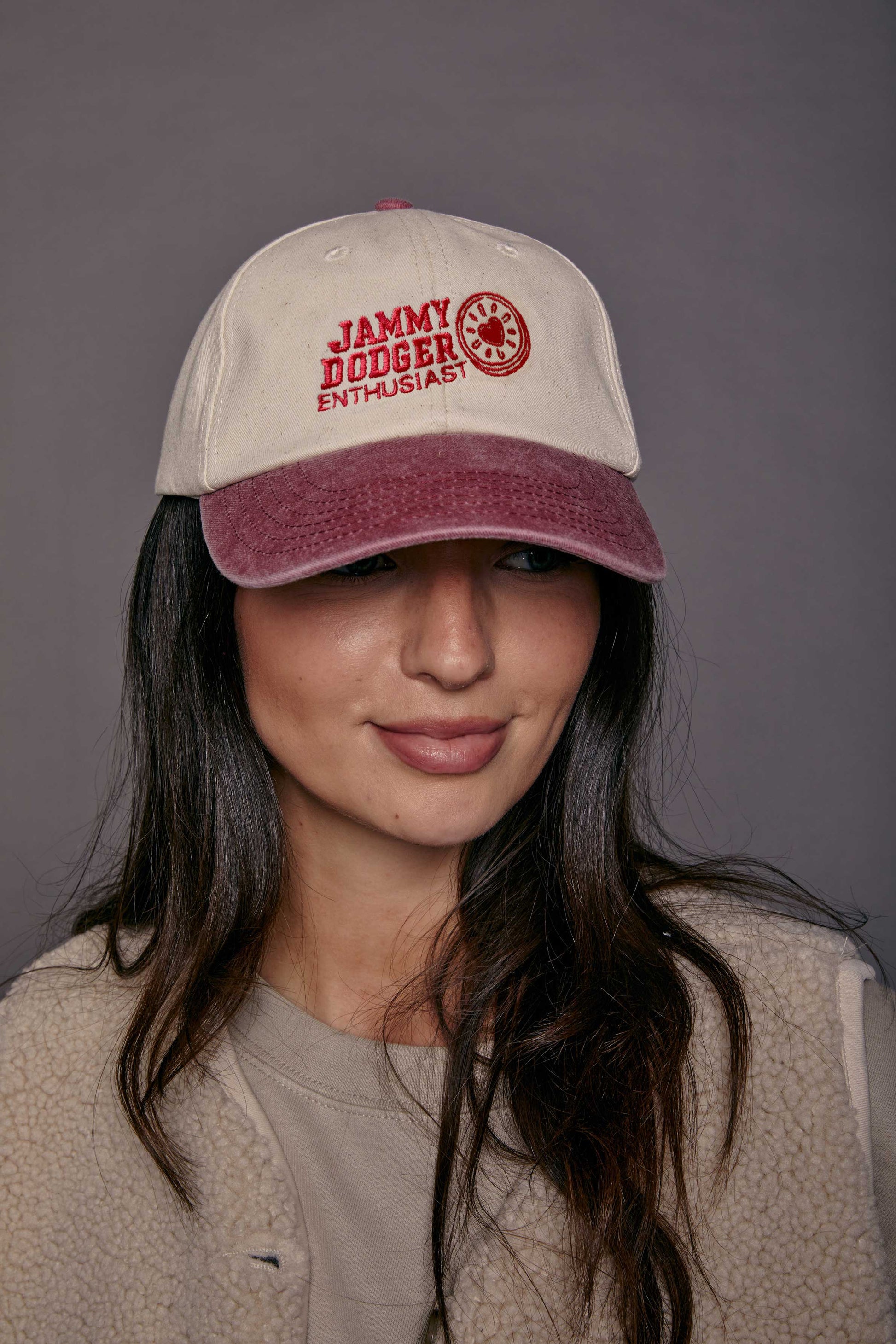 Woman wearing a cap with 'Jammy Dodger Enthusiast' text on a grey background