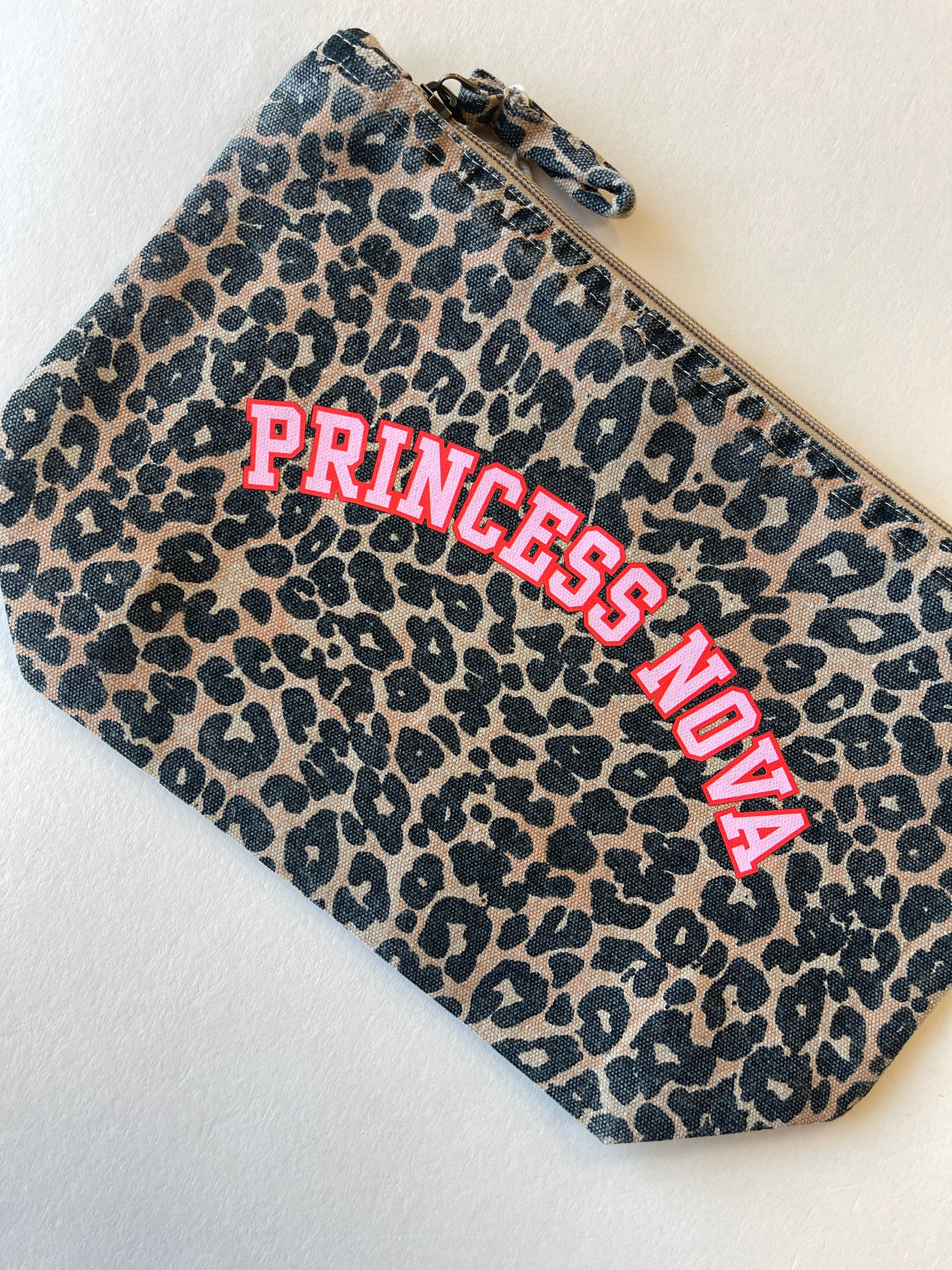 Leopard print zip pouch bag with 'Princess Nova' text in pink and red on a light background