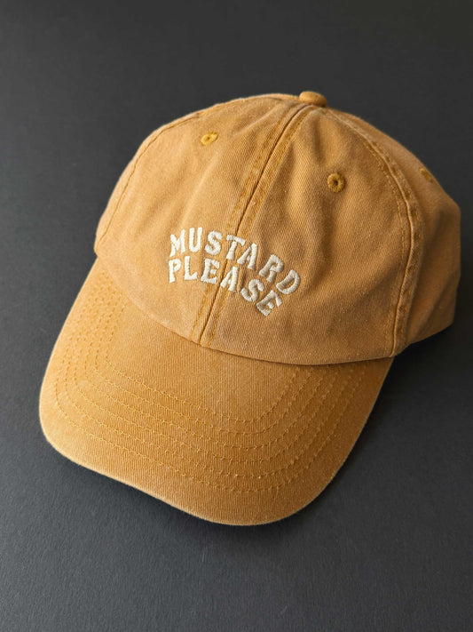 faded yellow cap with 'Mustard Please' text on a dark background