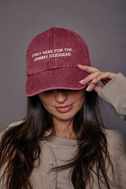 Person wearing a maroon cap with cream text, against a grey background