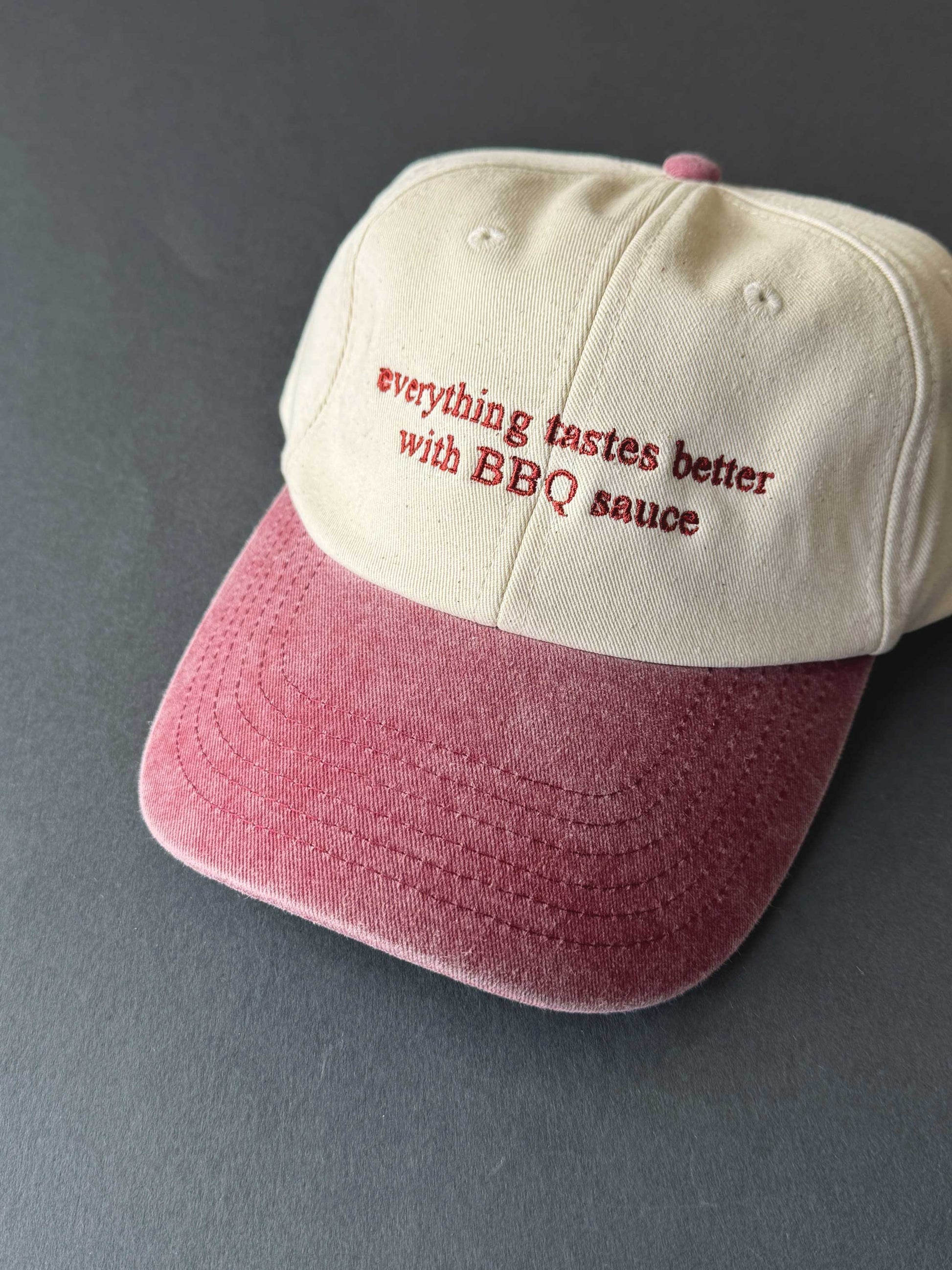 faded burgundy Cap with 'everything tastes better with BBQ sauce' text on a grey background