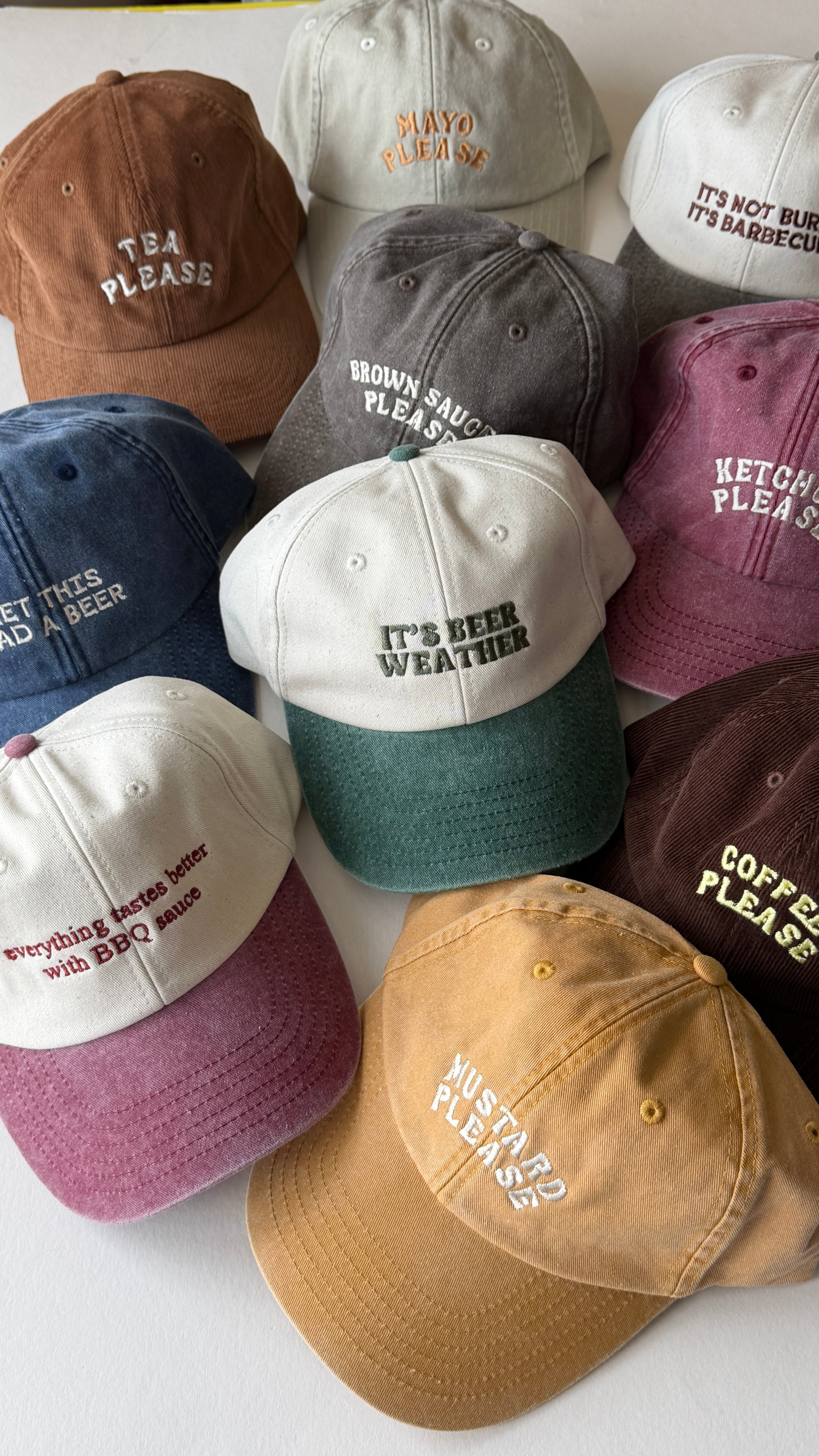 Collection of variously colored baseball caps with embroidered text on a white background