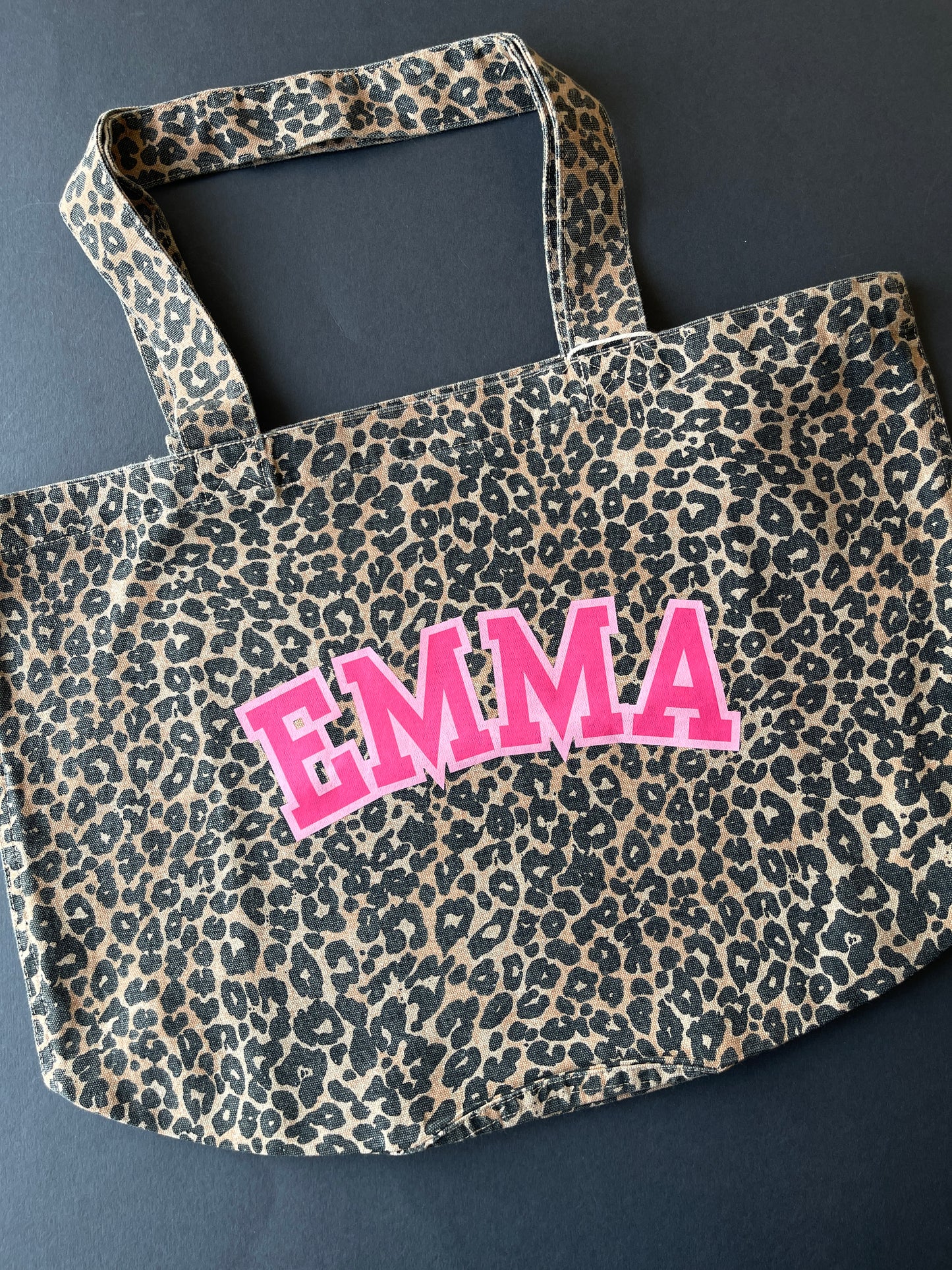 Leopard print bag with 'EMMA' in pink on a dark background