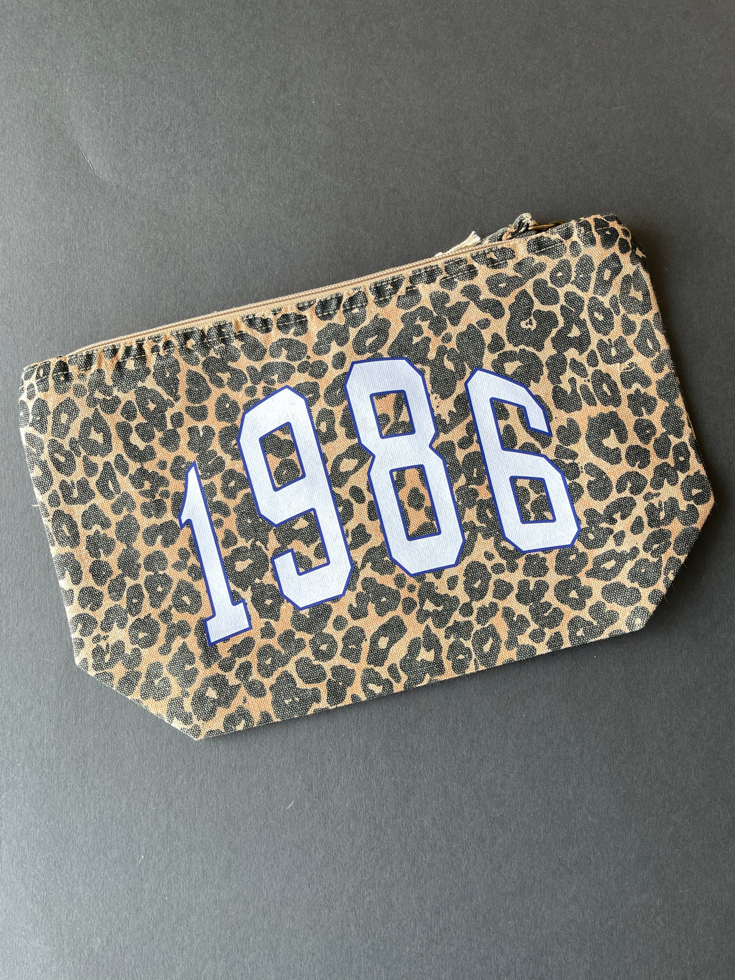 Leopard print zip pouch bag with '1986' year printed in pale blue and blue varsity style