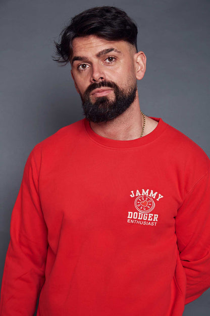 man wearing a bright red pullover sweatshirt printed with a jammy dodger design and slogan on the breast pocket that says 'Jammy Dodger Enthusiast'