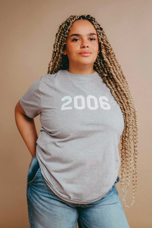 Person wearing a grey t-shirt with '2006' printed on it in white stood against a beige background