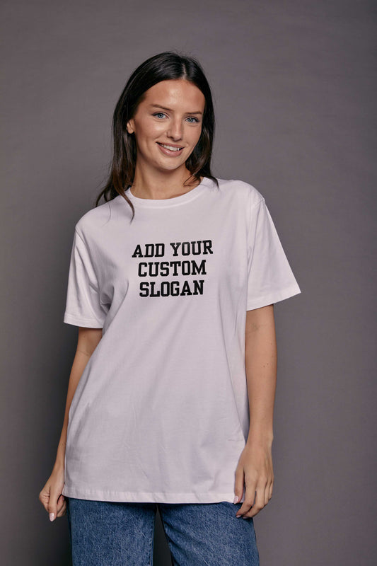 woman stood in front of a grey background wearing a white relaxed fit t shirt with the slogan 'add your custom slogan' printed on the front