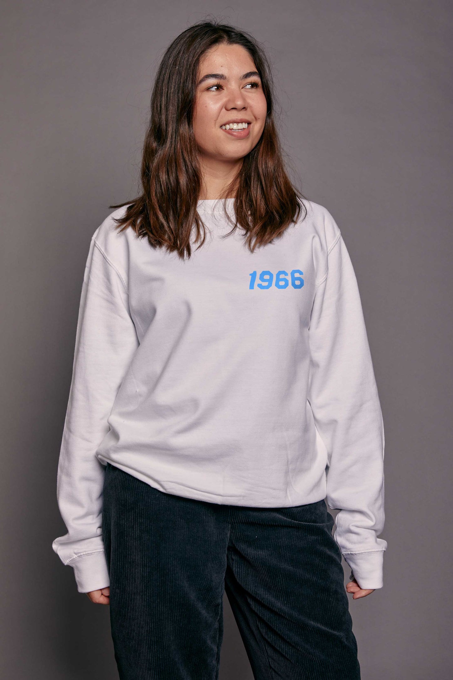 Person wearing a white sweatshirt with '1966' printed on it against a gray background