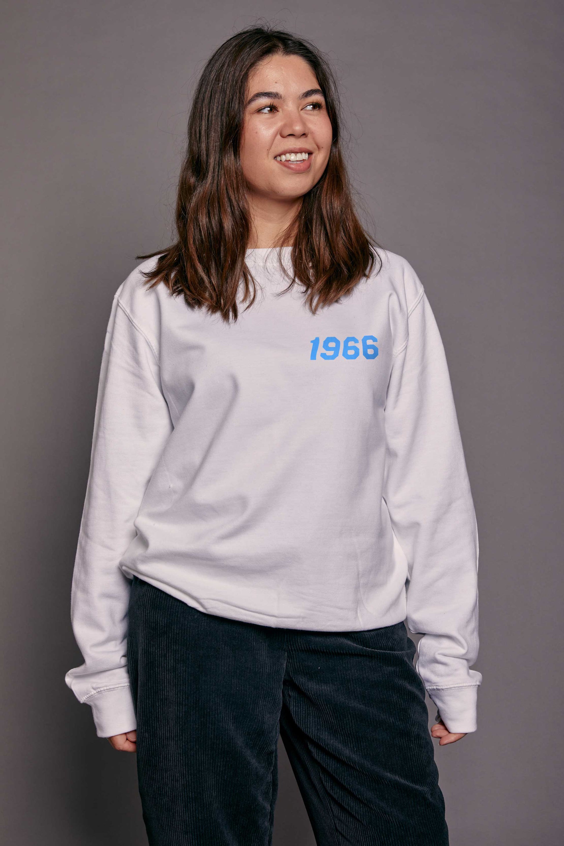 Person wearing a white sweatshirt with '1966' printed on it against a gray background